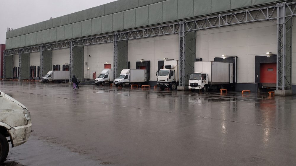 Доковая зона склада: защитное полотно закрывает верхний пояс над воротами, погрузка продолжается